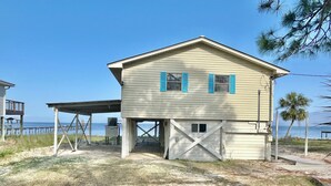 A coastal house with a covered porch, a garage, and a view of the ocean. - Bayside Cottage bayfront home with private dock (St. George Island)