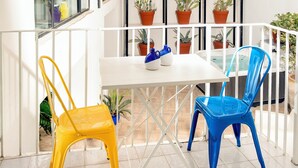 A balcony with a white table and chairs, surrounded by potted plants on shelves. - Capri Kronos Design Suites (Anacapri)