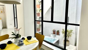 A modern kitchen with a round table, yellow chairs, and a window with potted plants. - Capri Kronos Design Suites (Anacapri)