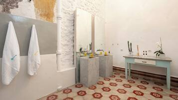 Un baño con dos lavamanos, un espejo, tocador y suelo estampado.
