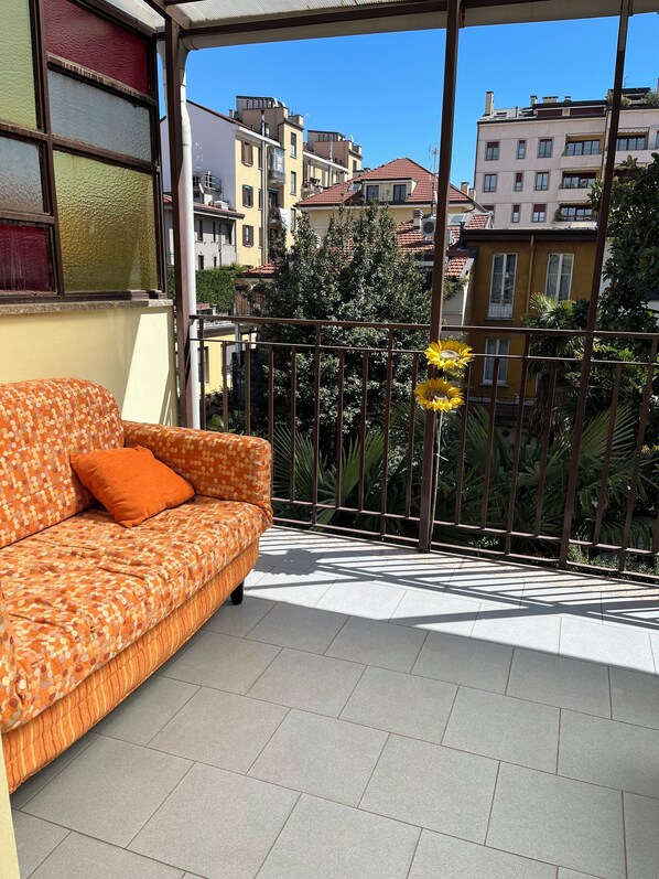 A balcony with a sofa and a flower decoration. - Appartamenti Aspromonte (Milan)
