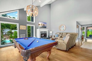 A pool table in a room with large windows, a fireplace, and a sofa. - The Tiki House - Stay for 28! (Osage Beach)