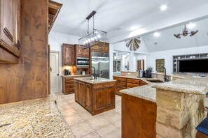 A spacious kitchen with wooden cabinets, granite countertops, stainless steel appliances, and a large island.