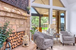 A cozy interior with a stone fireplace, two armchairs, and a table with a lamp.