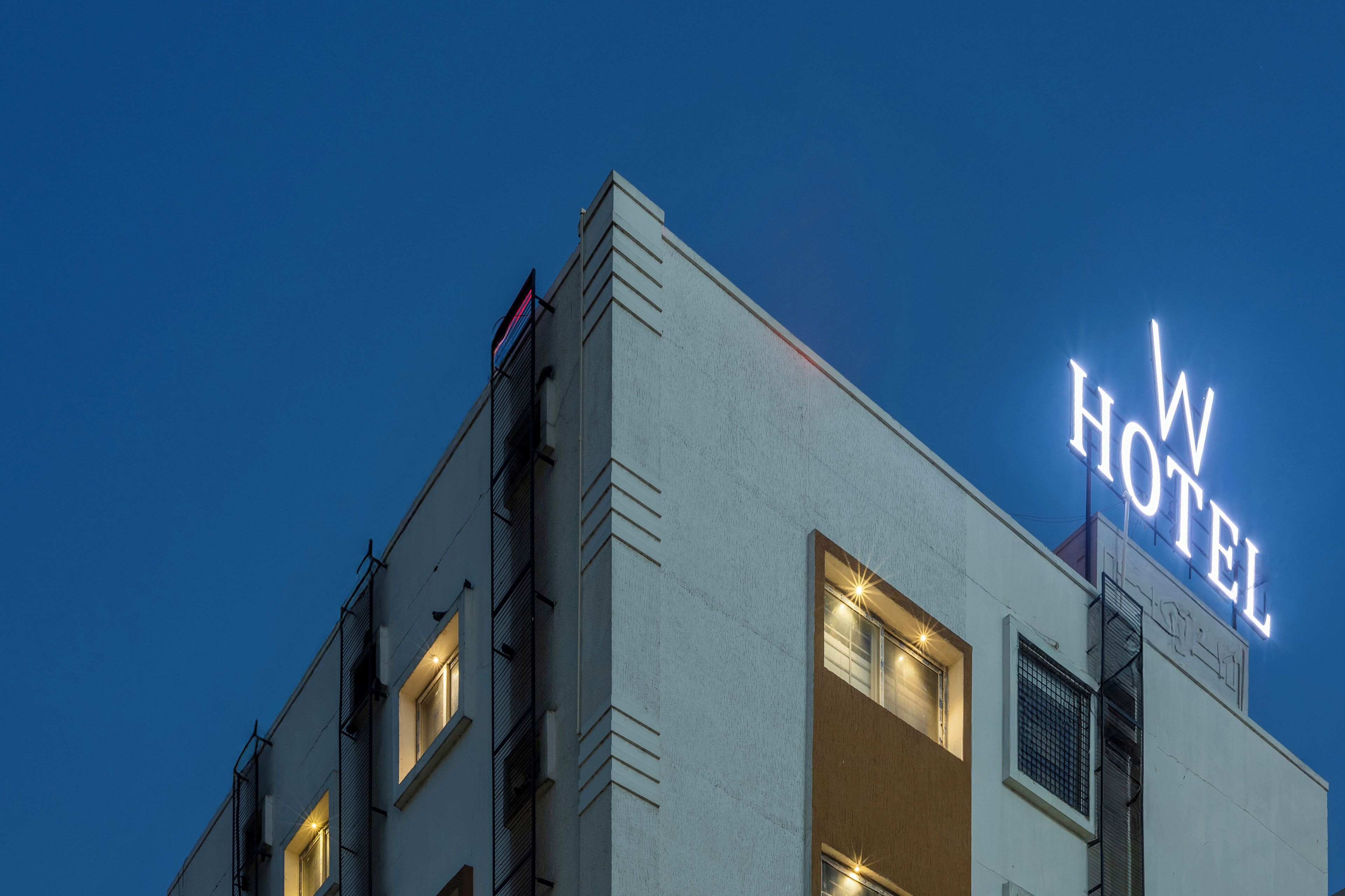 Un edificio con un cartel que dice "W HOTEL" contra un cielo al anochecer.