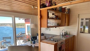 A cozy kitchen with wooden cabinets, a stove, and a dining area with a chair and table. - 4 Star Holiday Home in Stromstad (Stromstad)