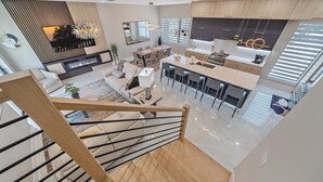 A spacious, modern kitchen with a central island, a dining area with a large table, and a living room with a sofa and a TV. - Uptown Oasis 3 Bedroom Townhouse (Sarasota)