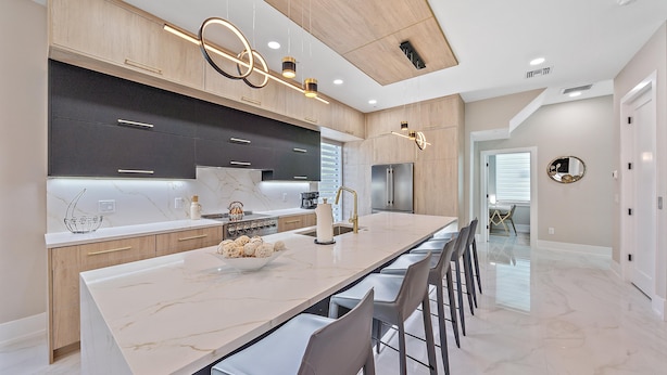 A modern kitchen with a marble countertop, stainless steel appliances, and pendant lighting. - Uptown Oasis 3 Bedroom Townhouse (Sarasota)