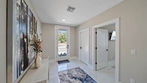 A hallway with a white door, a small rug, and a painting on the wall. - Uptown Oasis 3 Bedroom Townhouse (Sarasota)