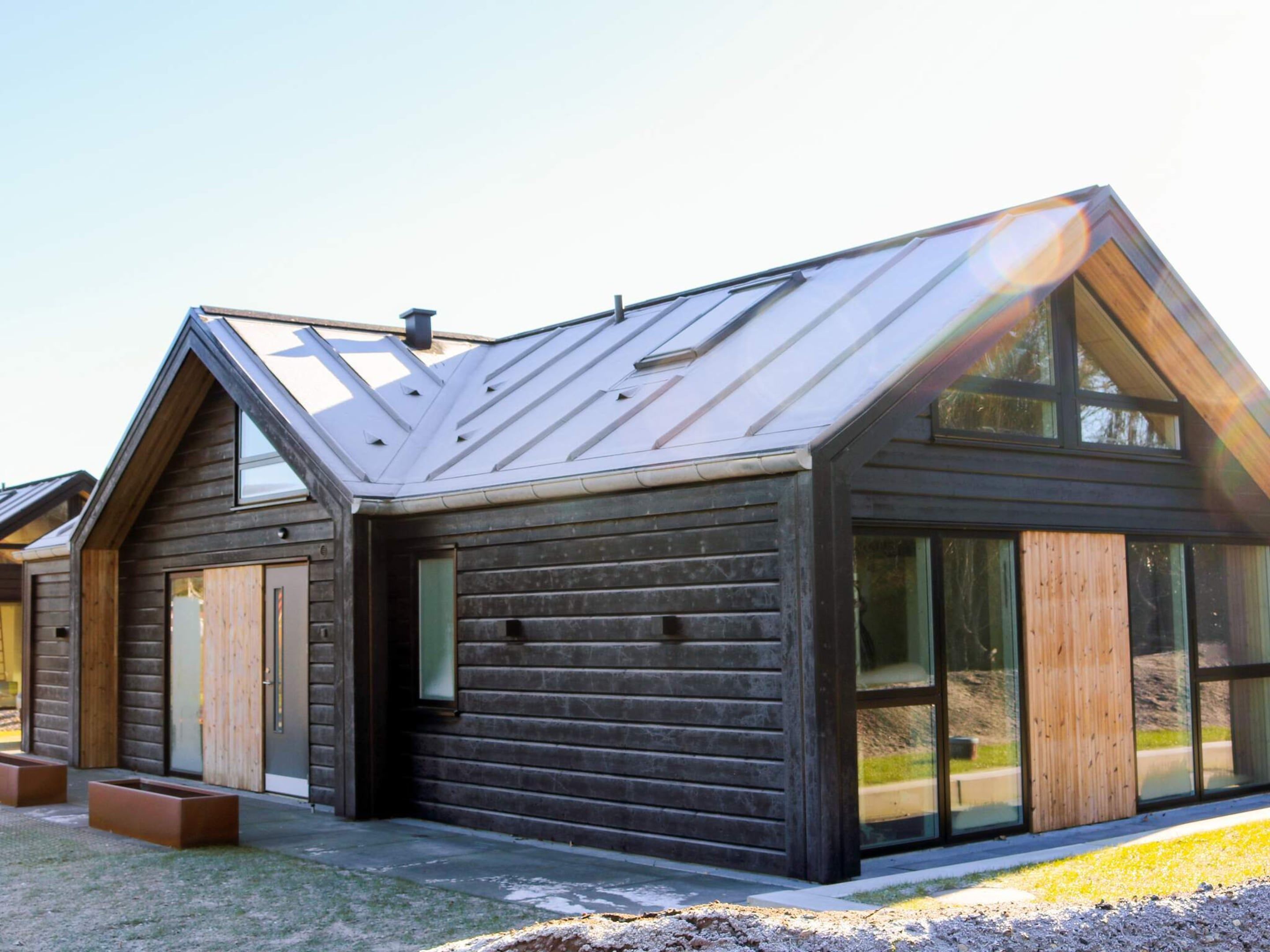 A modern log cabin with a sloped roof, large windows, and a small porch area.