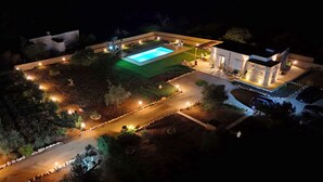 An aerial view of a well-lit residential property at night, featuring a swimming pool, a patio area, and a stone wall structure. - Tenuta alle Macchie, swimming pool, 4 guests, two bedrooms (Racale)