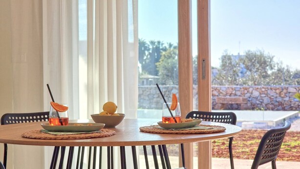 A round wooden table with two chairs, each with a woven placemat. There are two bowls on the table, each containing a glass of orange juice with a lemon slice and a straw. - Tenuta alle Macchie, swimming pool, 4 guests, two bedrooms (Racale)