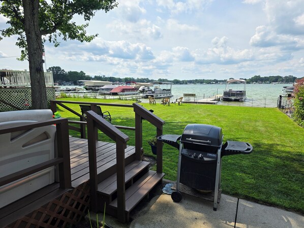 A deck with a grill and outdoor furniture overlooking a marina with boats.
