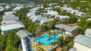 Luchtbeeld van een resort met meerdere gebouwen, een centraal gelegen zwembad en omliggend groen.
