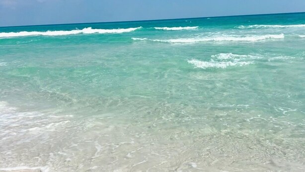 Een strand met helder turquoise water en een zandstrand.