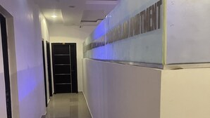 Un pasillo con piso de baldosas, un refrigerador a la derecha y una puerta al final.