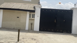 Un edificio de dos pisos con una puerta de garaje y un portón negro grande.