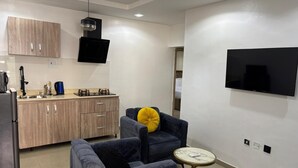 Una sala de estar moderna con un sofá, una mesita redonda y un televisor montado en la pared.