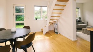 A modern interior with a dining area, wooden staircase, and a view of the outdoors. - 5 Star Holiday Home in Liseleje (Liseleje)