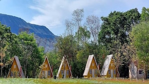 A row of yellow cabins with pitched roofs, surrounded by trees and a mountain in the background. - Itiquira Park Hotel (Formosa)
