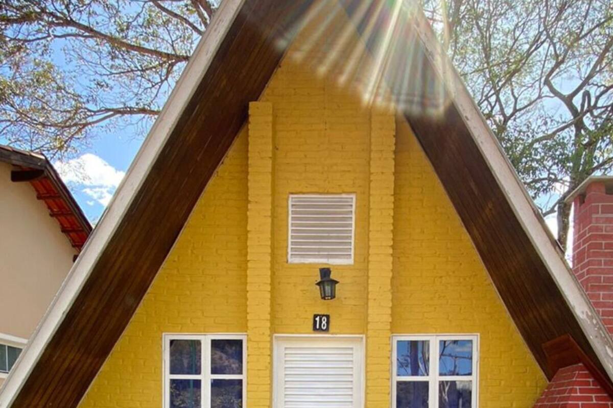 Un edificio de ladrillo amarillo con puerta y ventanas blancas, número 18, y una pequeña chimenea.