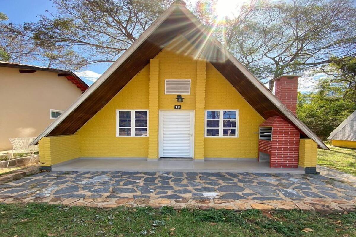 Una casa amarilla con un techo muy inclinado, una puerta de garaje blanca y una chimenea de ladrillo.