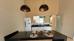 A modern kitchen with a central island, two pendant lights, a refrigerator, and a window with a view of greenery. - Itiquira Park Hotel (Formosa)
