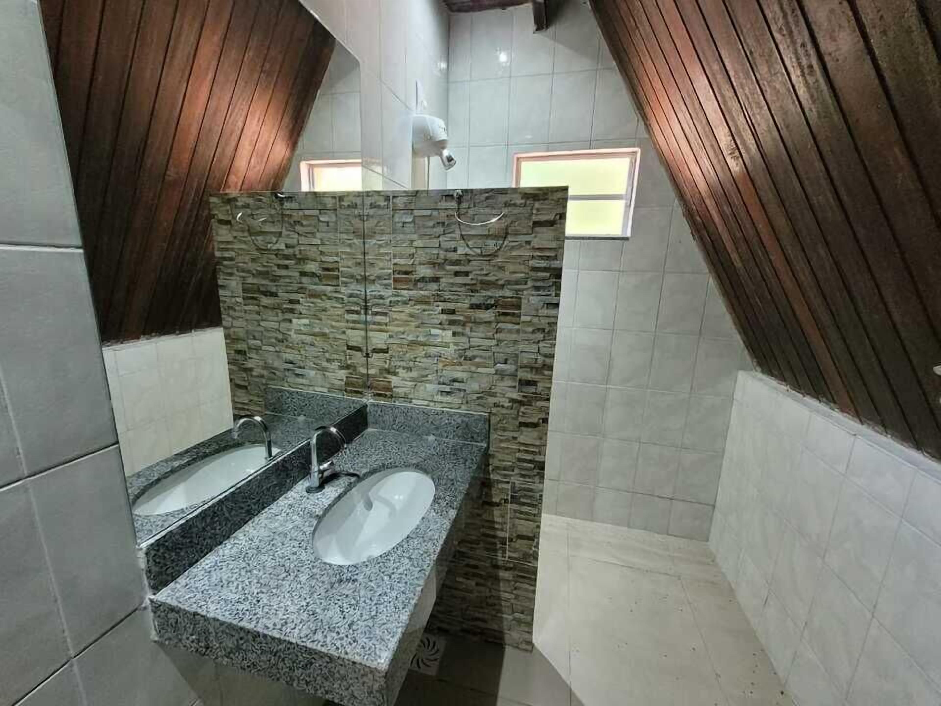 A bathroom with a stone wall, two sinks, and a wooden ceiling.