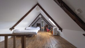 A small attic bedroom with wooden beams, a sloped ceiling, and a single bed. - Les Combes de Testas: Accommodation for 24 people, swimming pool, Aveyron Gorges (Sanvensa)