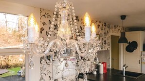 A kitchen with a chandelier, floral wallpaper, and a view of the outdoors. - 4 Person Holiday Home in Vordingborg (Vordingborg)