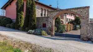 A traditional stone house with a pink facade, a gravel driveway, and a gated entrance. - Casa Rondinella By Case al Lago (Cavriana)