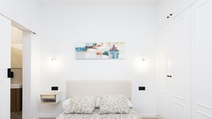 Un dormitorio con cama, mesita de noche, una obra de arte en la pared y armario.