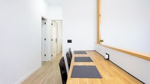 Una habitación moderna y minimalista con una mesa de comedor de madera, sillas negras y una pequeña planta en maceta.