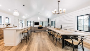 Una cocina moderna con una isla central, taburetes de bar y una mesa de comedor.