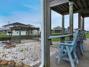A wooden deck with benches, a covered area, and a view of houses in the background.