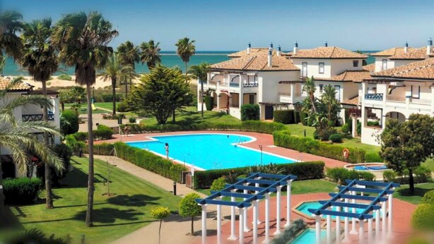 A resort with a central swimming pool, palm trees, and a view of the sea. - San Bruno 73 - Two Bedroom Apartment, Sleeps 5 (Punta del moral)
