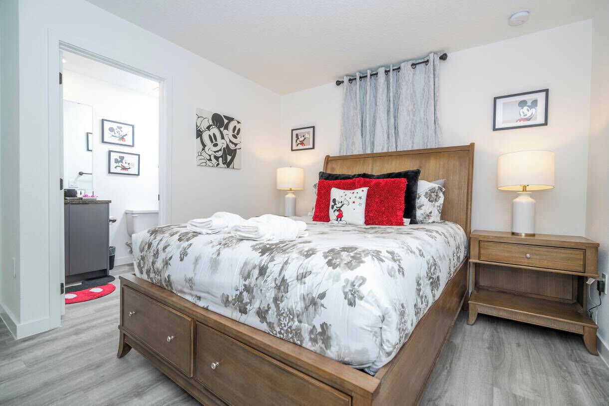 A bedroom with a wooden bed, two bedside tables with lamps, and wall art.