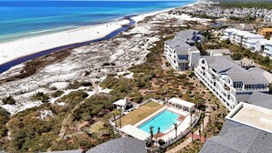 Un resort con piscina, acceso a la playa y varias construcciones.