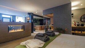 A modern hotel room with a large bed, a fireplace, a view of the city, and a cozy seating area. - Relax in Wellness Room with Sauna and Spa Bath and luxurious outdoor seating. (Nieuwe Niedorp)