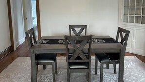 A dining area with a dark wooden table and chairs, a patterned rug, and a ceiling light fixture. - Charming 2-bedroom apartment in Saint Paul. Near MAC, UST, St. Kate's. (Saint Paul)