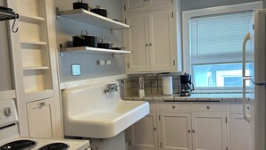 A kitchen with white cabinets, a white sink, a stove, and a window with blinds. - Charming 2-bedroom apartment in Saint Paul. Near MAC, UST, St. Kate's. (Saint Paul)