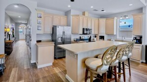 A modern kitchen with a central island, stainless steel appliances, and light wood cabinetry. - Beachfront Stay! BBQ, Lanai and Cozy Beds! (Bradenton Beach)