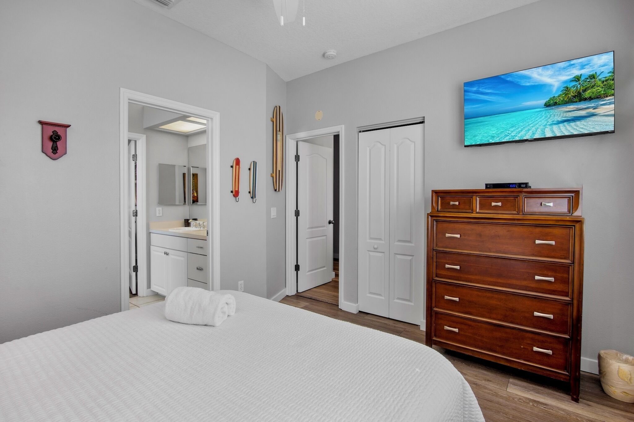 Un dormitorio con una cama grande, un aparador, un televisor y una puerta que da a otra habitación.