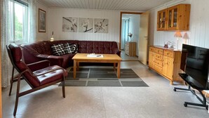 Un salon chaleureux avec un canapé en cuir, une table basse en bois et un téléviseur.