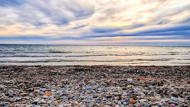 Une plage bordée d’un rivage rocheux, sous un ciel nuageux.