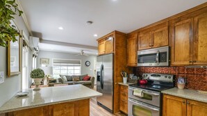 A kitchen with wooden cabinets, stainless steel appliances, and a granite countertop. - Charming 2-bedroom house in historic Mount Dora with WiFi, AC, & full kitchen (Mount Dora)
