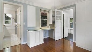 A spacious kitchen with white cabinetry, a window, and a door leading to another room. - Charming 2-bedroom house in historic Mount Dora with WiFi, AC, & full kitchen (Mount Dora)