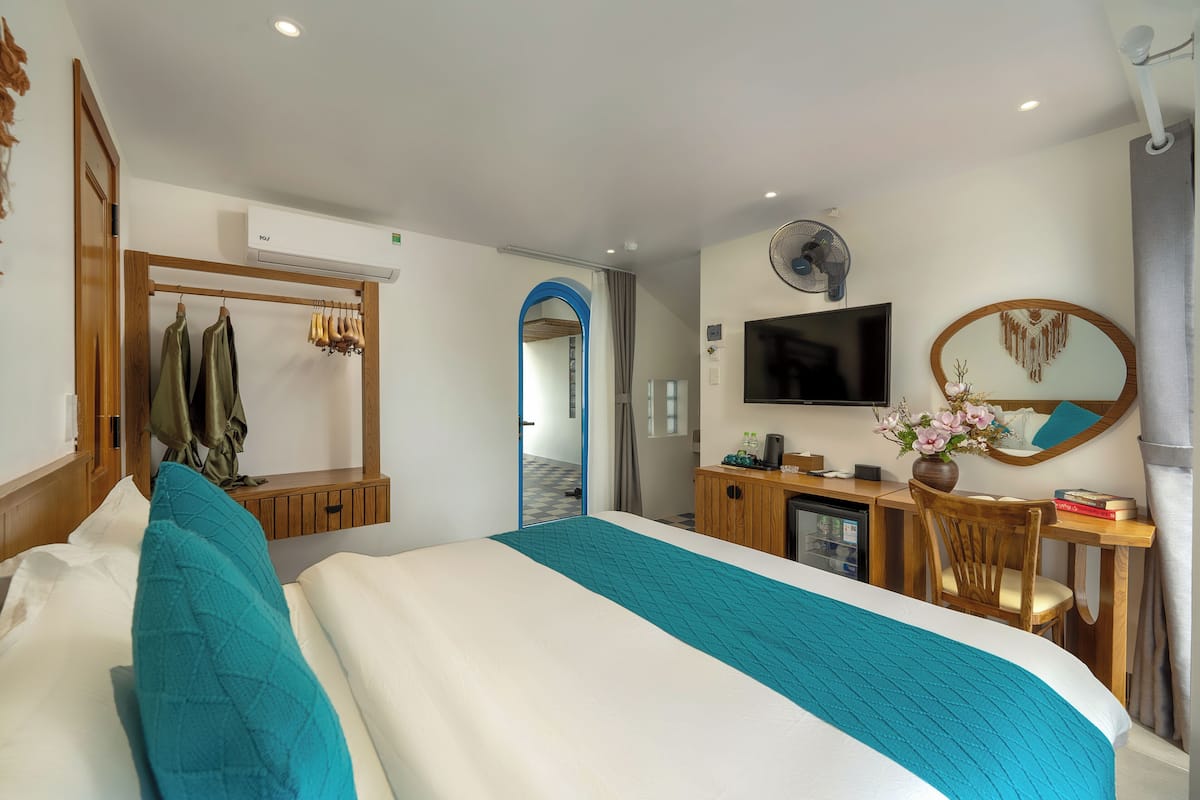 A hotel room with a bed, a desk, a TV, and a mirror.