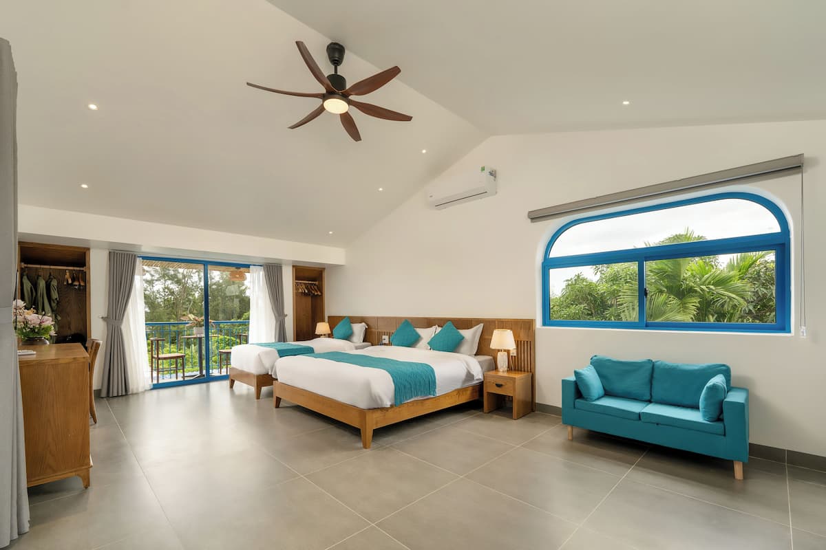 A spacious bedroom with a large bed, a sofa, and a ceiling fan.