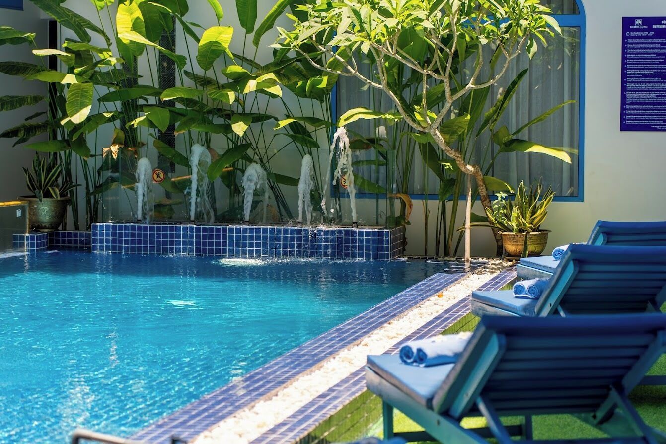 A swimming pool with lounge chairs, surrounded by potted plants and a tiled deck.